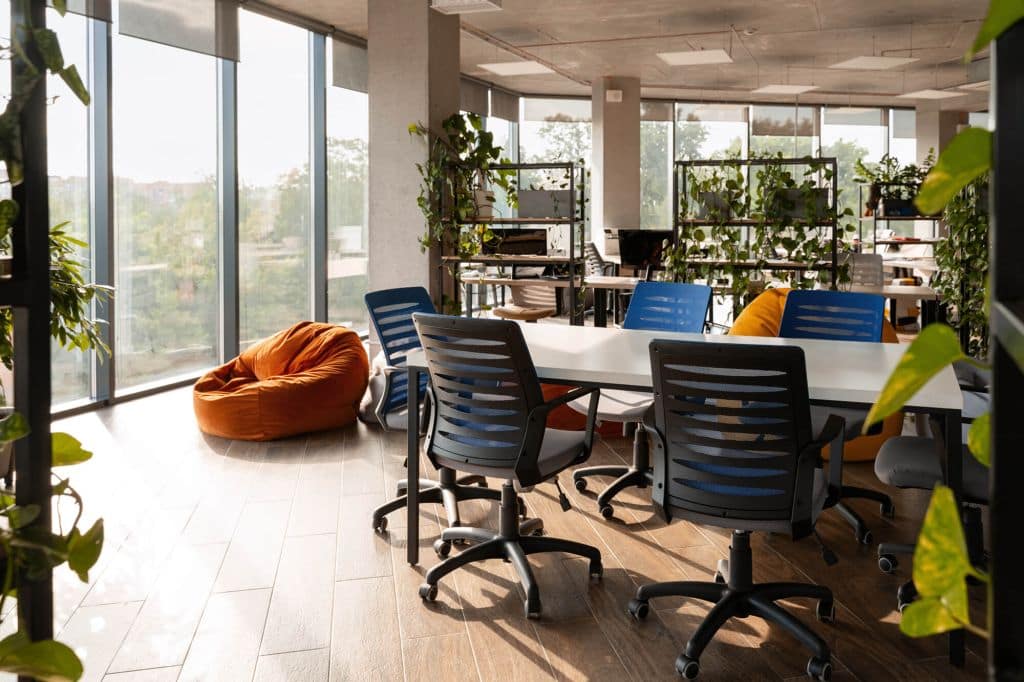 Coworking open space interior with hot desks, ergonomic seating, and professional lighting.